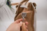 Side view of a handmade cork tote bag crafted from sustainable Portuguese cork. The bag features a light gray cork exterior with natural cork accents, sturdy dual handles, an adjustable shoulder strap, and a secure top zipper closure. The spacious design includes multiple compartments, combining elegant style with eco-friendly functionality.